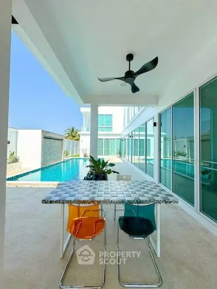 Luxurious modern poolside patio with stylish furniture and ceiling fan
