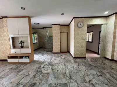 Spacious living room with elegant marble flooring and stylish wallpaper, featuring a built-in cabinet and staircase.