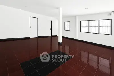 Spacious empty room with glossy dark tile flooring and white walls, ideal for customization.