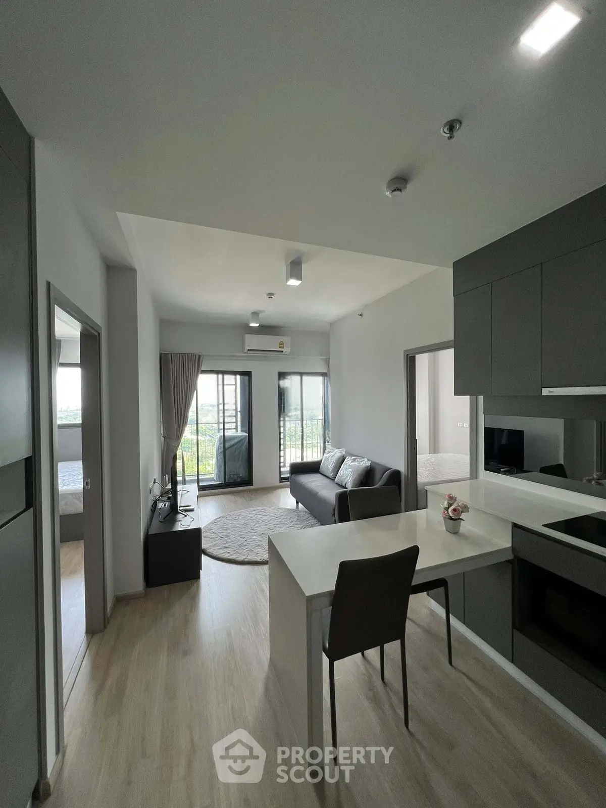 Modern open-plan living room with sleek kitchen and balcony view, perfect for urban living.