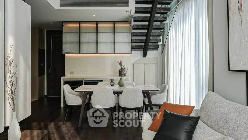Modern living room with elegant dining area and stylish staircase in a contemporary home.