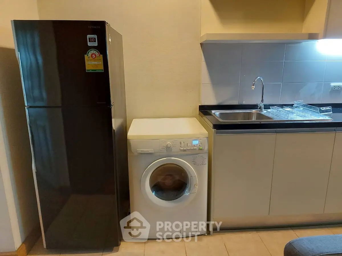 Modern kitchen with fridge and washing machine in compact layout