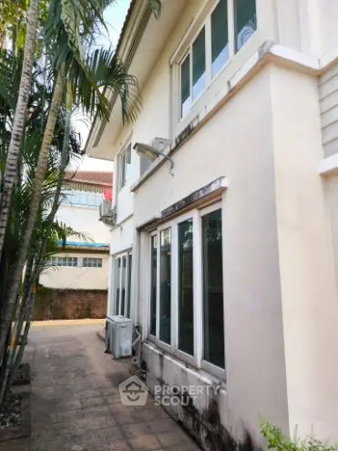Charming two-story house with lush palm trees and spacious outdoor area.