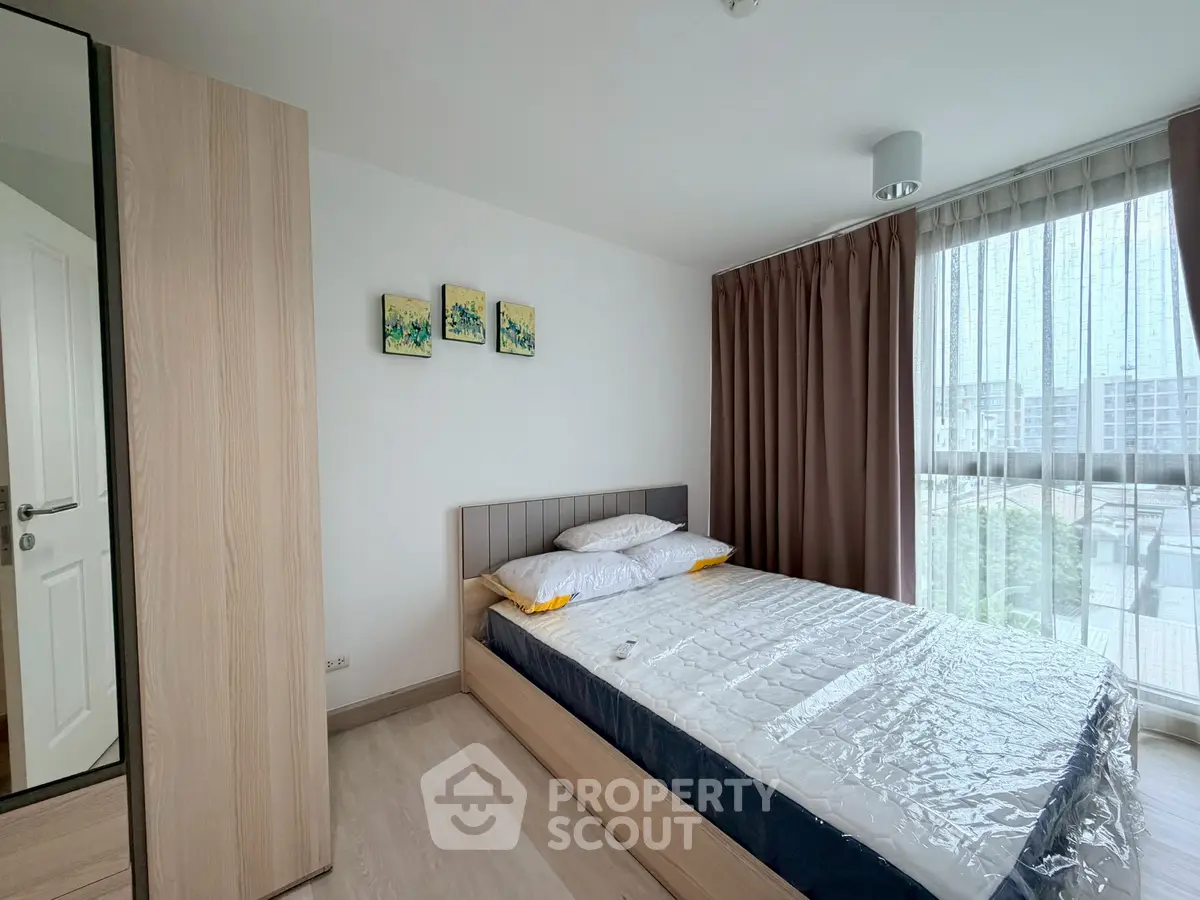 Modern bedroom with large window and stylish decor in a contemporary apartment.