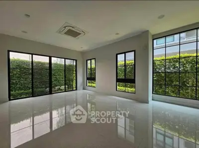 Spacious modern living room with large windows and garden view, perfect for natural light lovers.