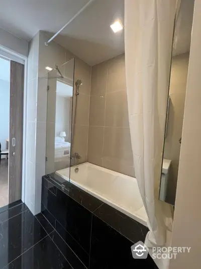 Modern bathroom with sleek bathtub and glass shower partition in luxury apartment