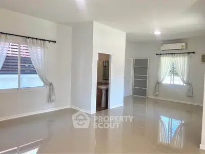 Spacious and bright living area with glossy tiled floors and large windows.