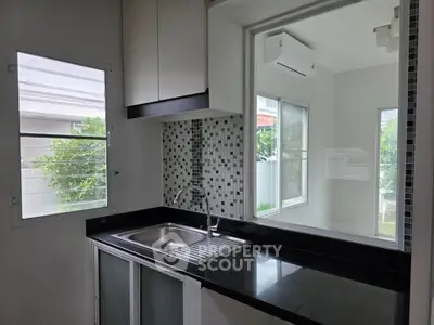 Modern kitchen with sleek black countertop and large windows for natural light