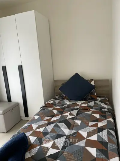 Cozy bedroom with modern geometric bedding and sleek white wardrobe, perfect for urban living.