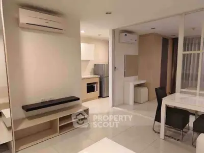 Modern open-plan living and dining area with sleek kitchen appliances and air conditioning.
