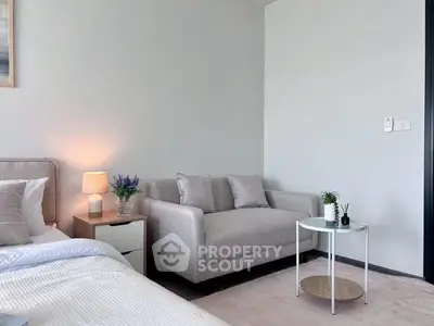 Cozy bedroom with modern decor, featuring a comfortable bed and stylish sofa, perfect for relaxation.