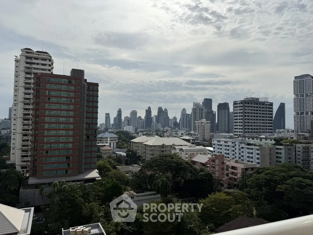 Stunning cityscape view from a high-rise balcony showcasing urban skyline and lush greenery.
