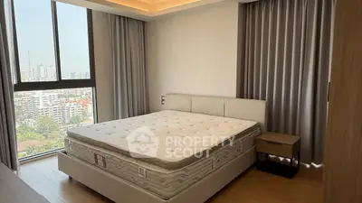 Spacious bedroom with city view and modern furnishings in high-rise apartment.