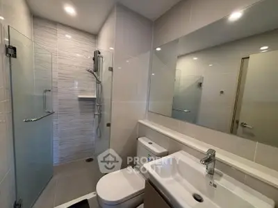 Modern bathroom with glass shower and sleek fixtures in contemporary apartment.