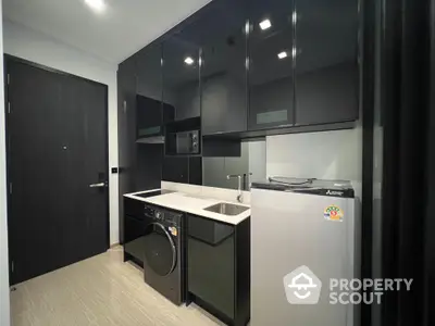 Modern compact kitchen with sleek black cabinets and built-in appliances