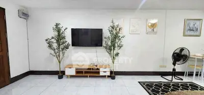 Modern living room with wall-mounted TV, stylish decor, and indoor plants for a cozy ambiance.