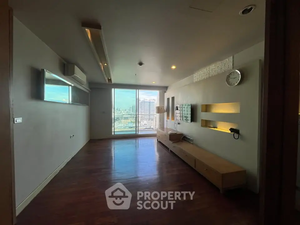 Spacious living room with wooden flooring and large window offering city view
