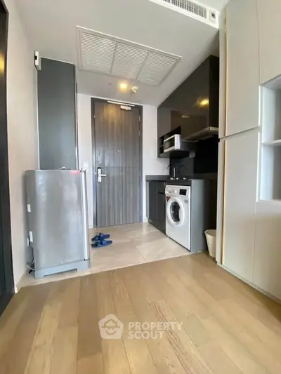 Modern kitchen with washing machine and sleek appliances in compact apartment.