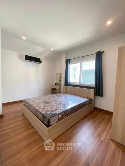 Spacious bedroom with wooden flooring and modern furnishings