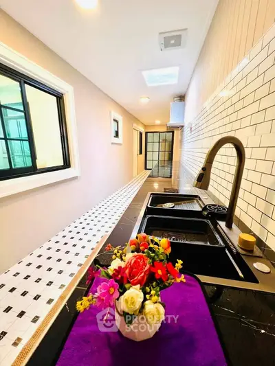 Sleek modern kitchen with stylish black sink and vibrant flower arrangement, perfect for culinary enthusiasts.