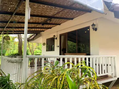 Charming tropical home with spacious wooden deck and lush garden view, perfect for relaxation and outdoor living.