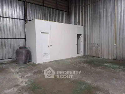 Spacious industrial warehouse with metal walls and a small interior room, ideal for storage.