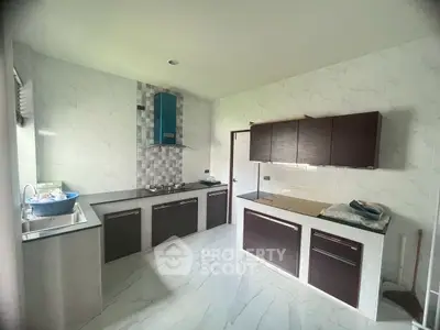 Modern kitchen with sleek cabinetry and marble flooring, featuring a gas stove and ample natural light.