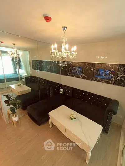 Luxurious living room with elegant chandelier and plush black sofa in modern apartment.