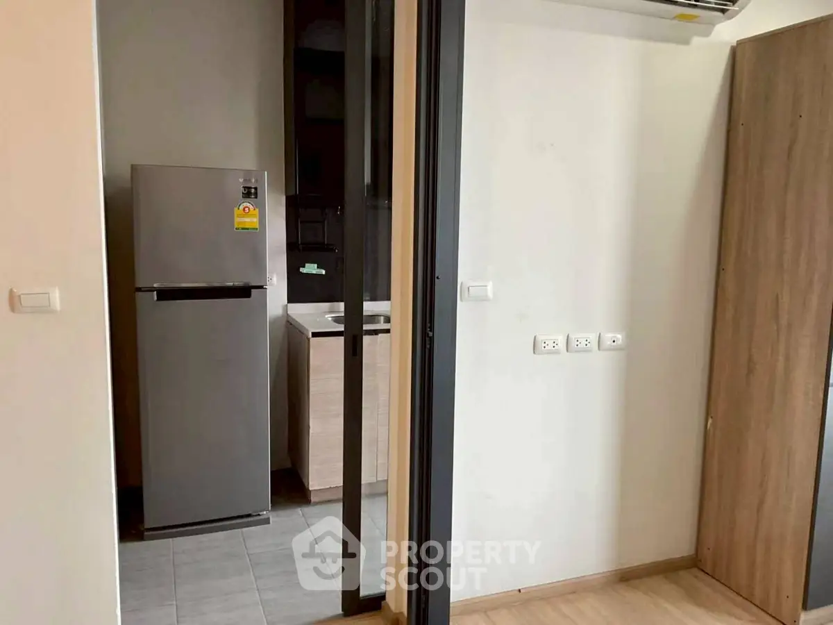 Modern kitchen with sleek fridge and minimalist design in a compact space.
