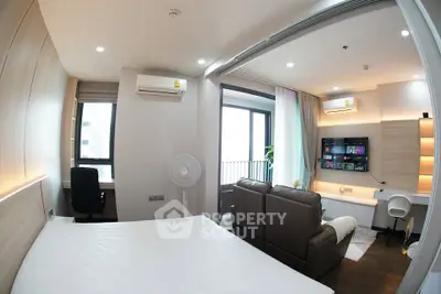 Modern studio apartment with sleek design, featuring a cozy living area and balcony access.