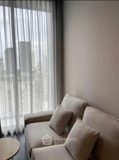 Cozy living room with modern sofa and city view through sheer curtains.