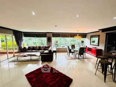 Spacious living room with modern decor and large windows offering lush garden views.