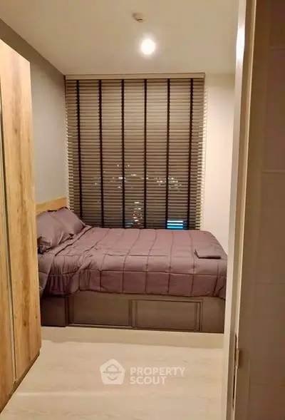 Cozy bedroom with modern decor and city view through blinds