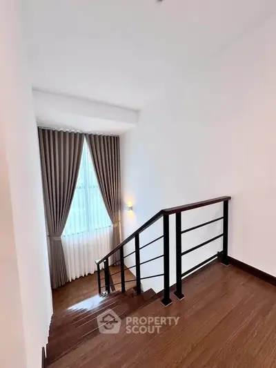 Elegant staircase with wooden flooring and modern railing in a bright interior space.