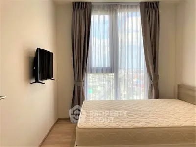 Modern bedroom with large window and wall-mounted TV in a stylish apartment.