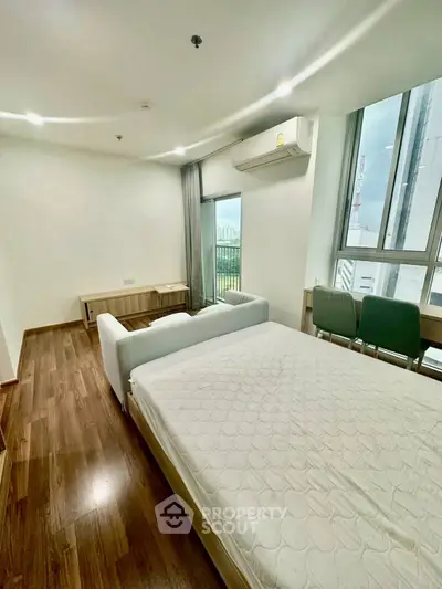 Modern bedroom with wooden flooring and large windows offering city views