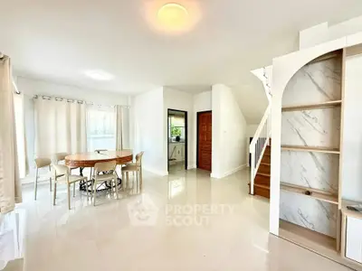 Spacious open-plan living area with elegant dining set and modern staircase