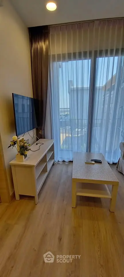 Charming living room with modern decor and large window offering natural light and balcony access.