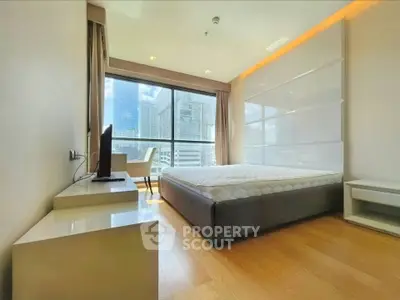 Modern bedroom with large window offering stunning city view in high-rise apartment.