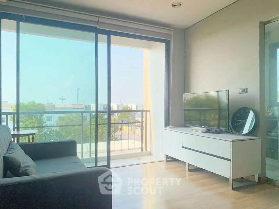 Bright living room with balcony view, modern furniture, and natural light.