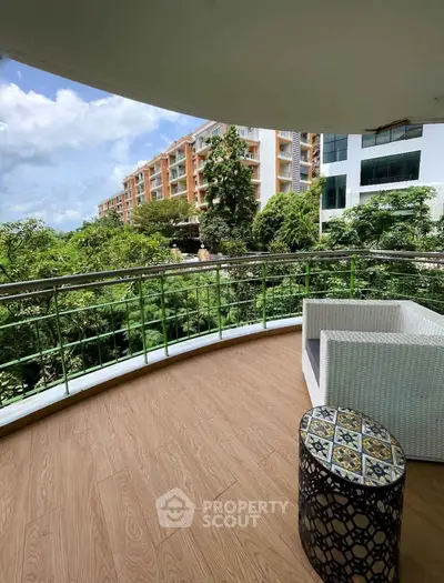 Spacious balcony with scenic view of lush greenery and modern buildings, perfect for relaxation.