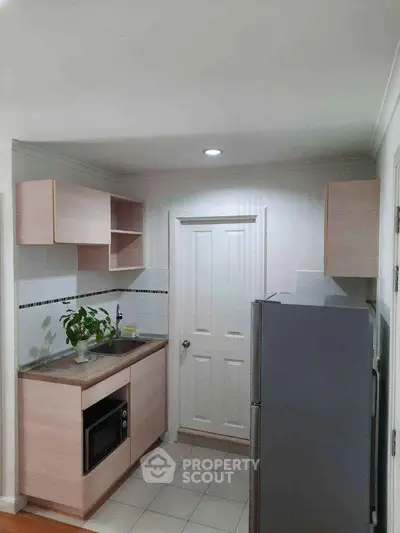 Modern compact kitchen with sleek cabinetry and stainless steel fridge