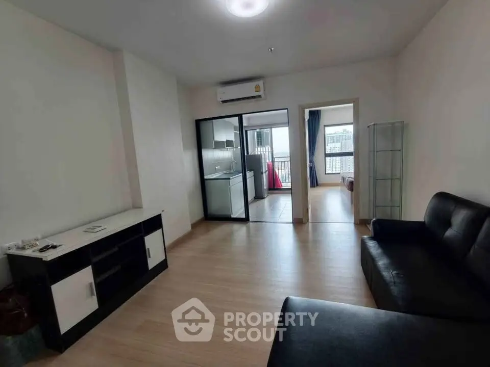 Spacious modern living room with sleek furniture and open layout, leading to a bright balcony view.