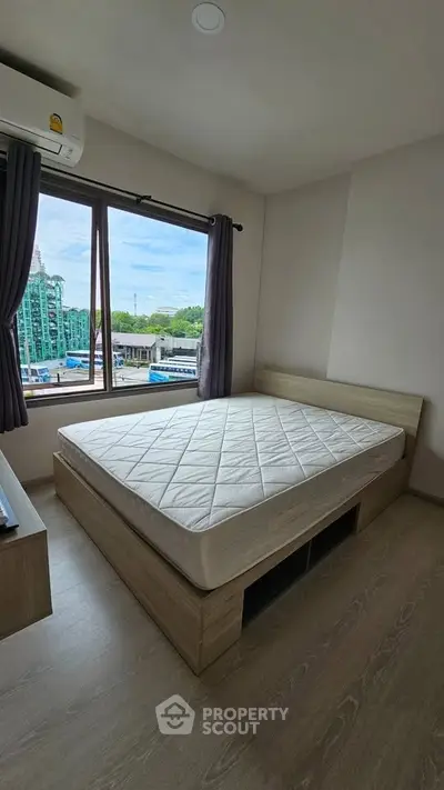 Cozy bedroom with large window offering city view, featuring a comfortable bed and modern decor.