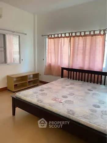 Spacious bedroom with natural light and simple furnishings, ideal for comfortable living.