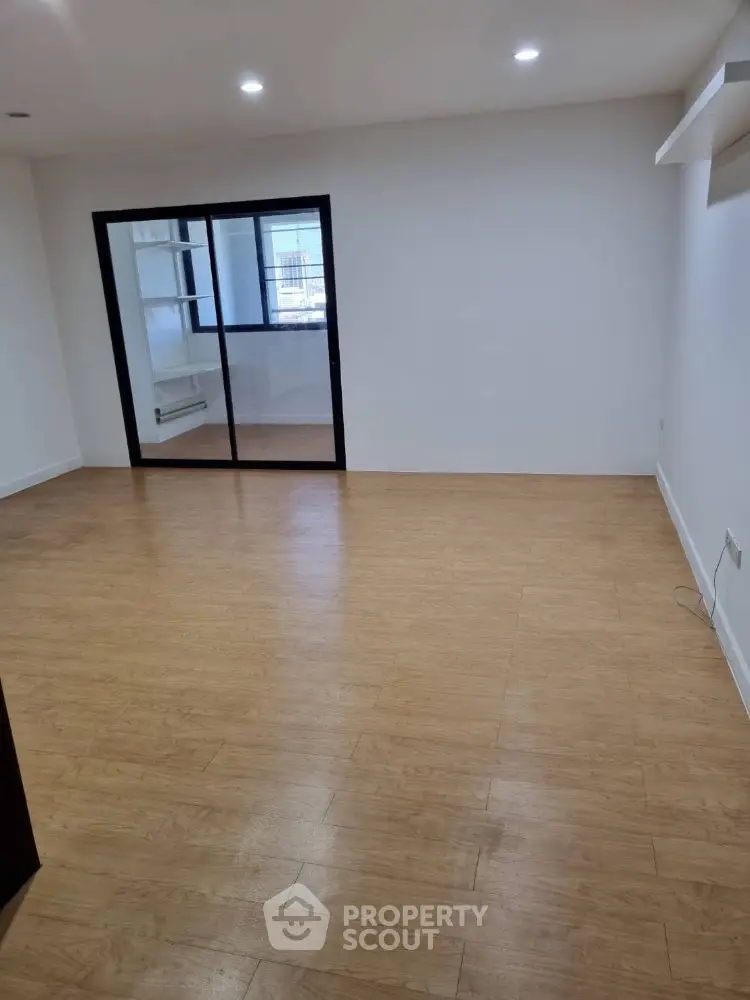 Spacious empty room with wooden flooring and glass sliding doors