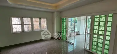 Spacious living room with large windows and sliding glass doors, featuring modern ceiling design and glossy flooring.