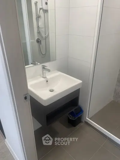 Modern bathroom with sleek sink and shower in contemporary apartment.