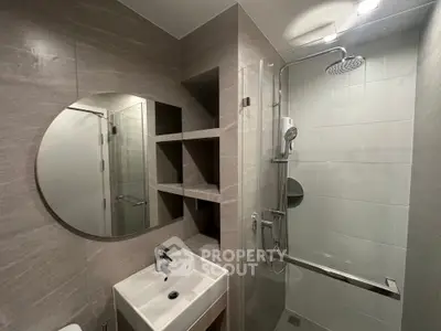 Modern bathroom with sleek shower and round mirror in stylish apartment