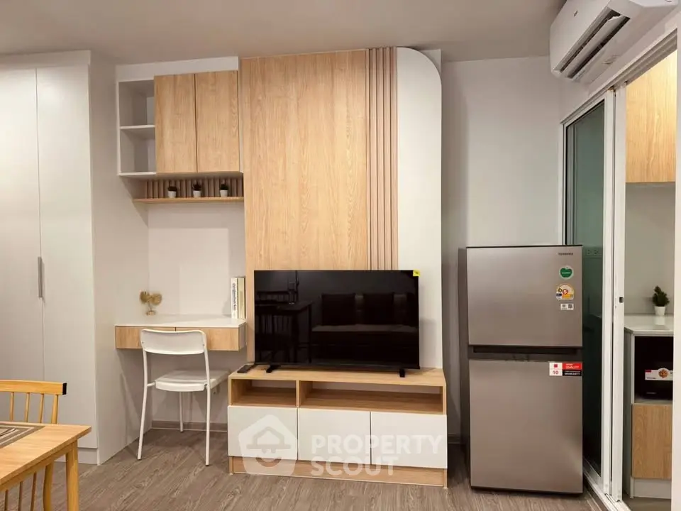Modern living room with sleek furniture and integrated kitchen appliances in a cozy apartment.